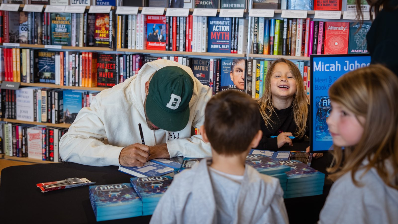 Micah signing copies of Aku: Journey to Ibra for kids at a bookstore
